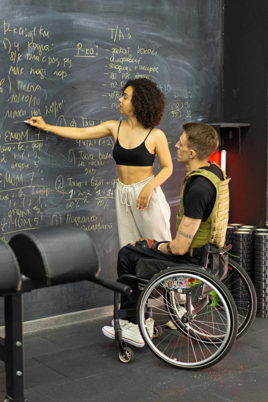 a female student writing on a blackboard and sitting in front of a man