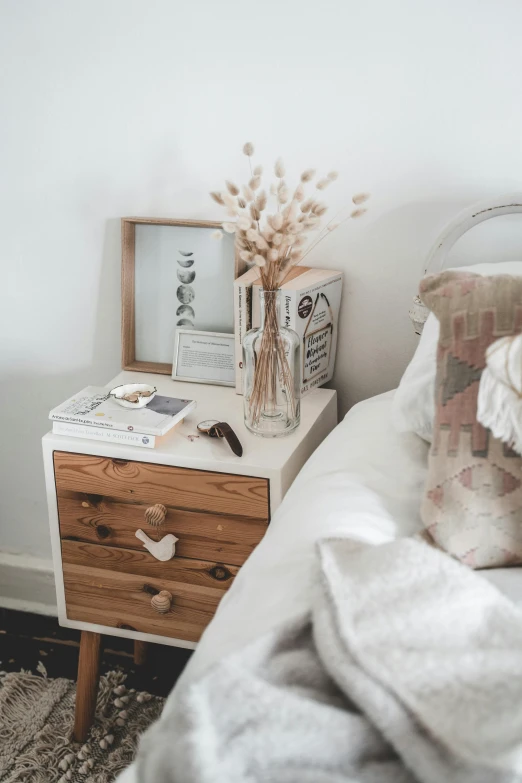 a white bed with a wooden dresser topped with flowers