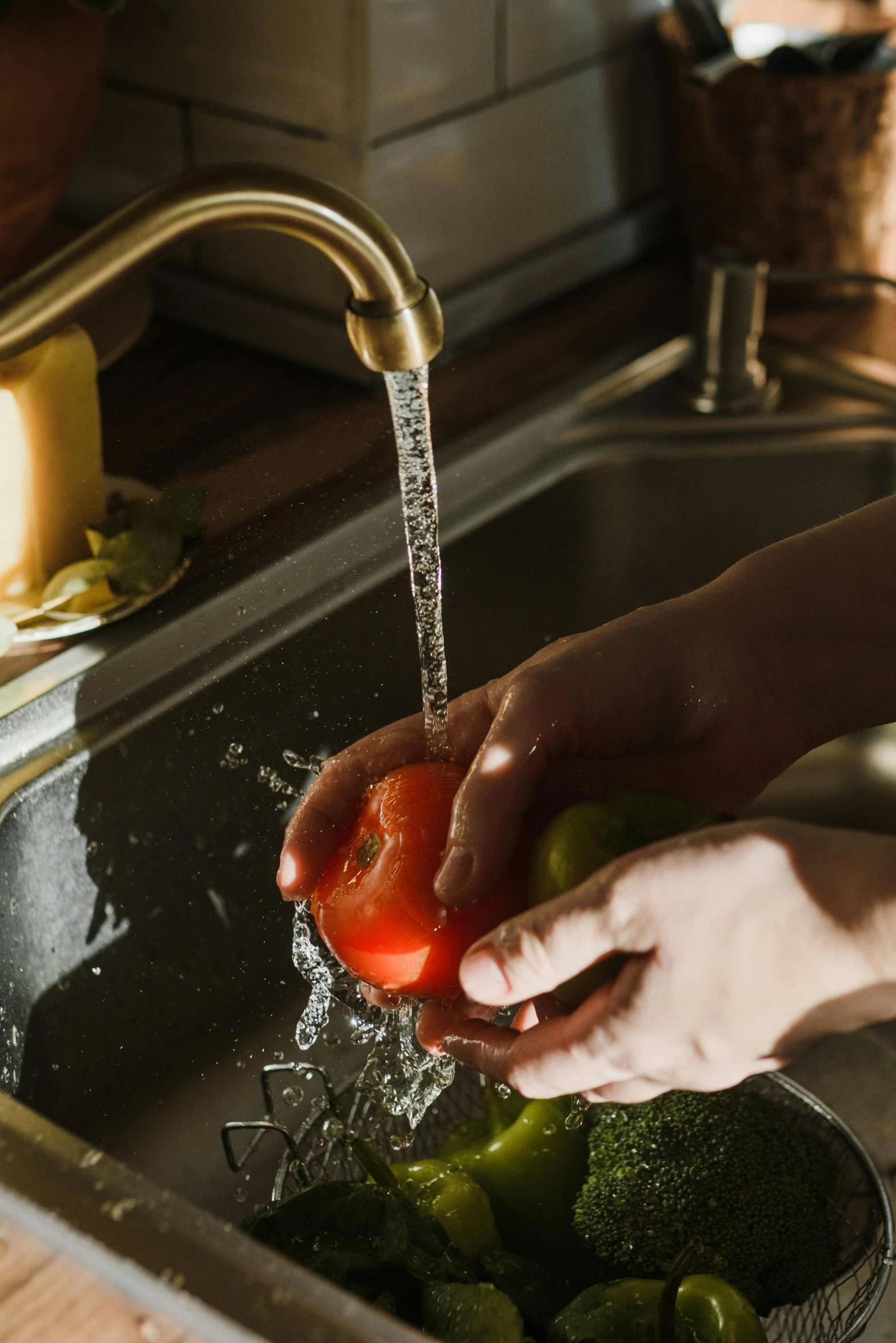 a person washing vegetables in a sink under a faucet