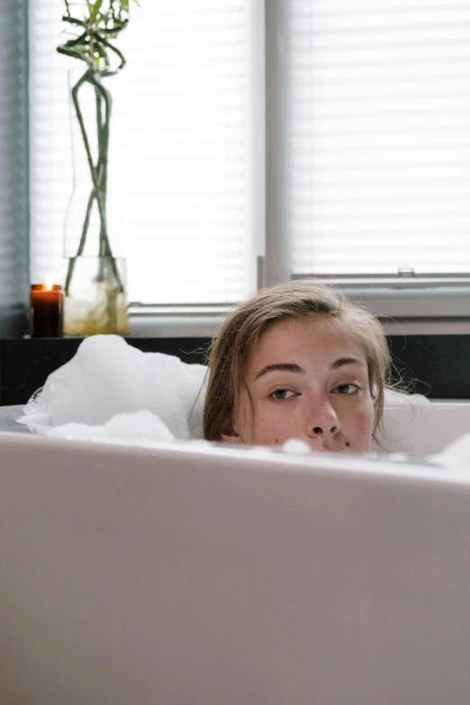 a girl is in a bathtub with her head turned towards the side