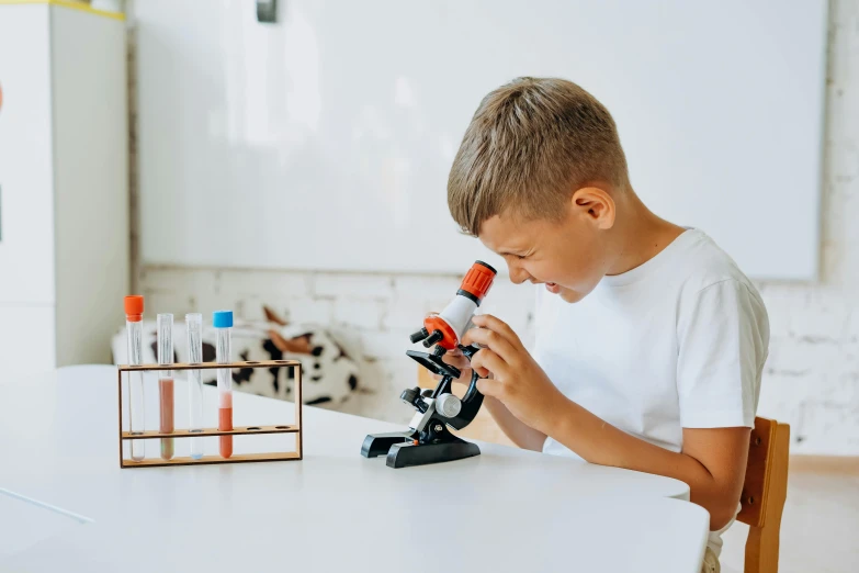  looking through a microscope in a white kitchen