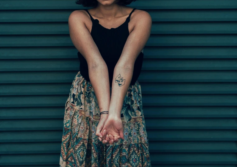 a woman standing against a green wall holding her hand over her belly