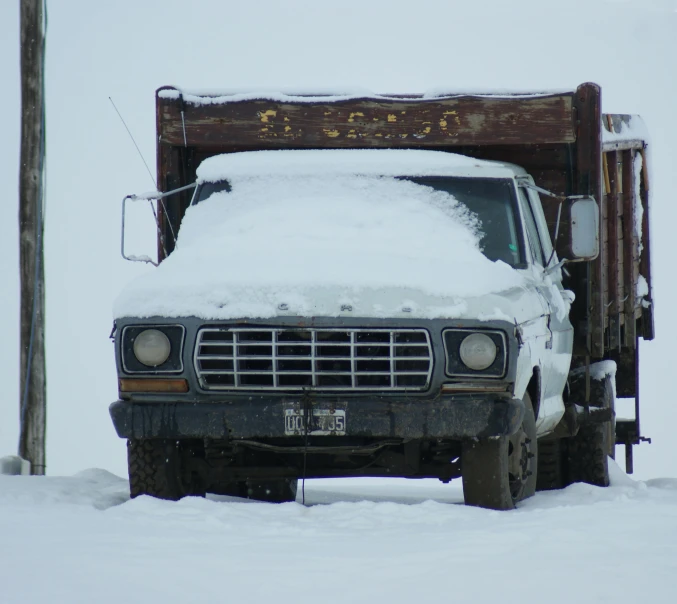 a flat bed truck is covered in snow