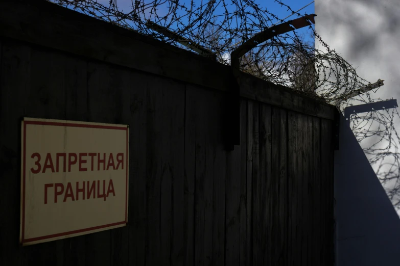 a barbed fence and building with a sign hanging from it