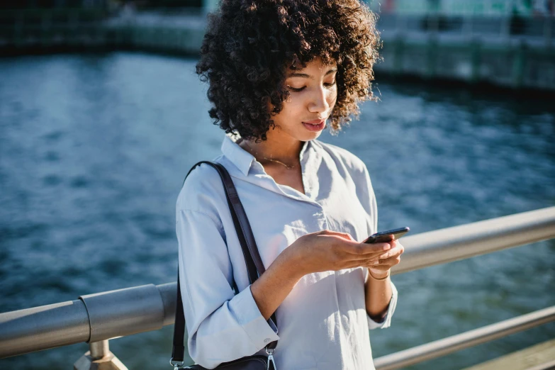 a woman looking at her phone while standing near the river