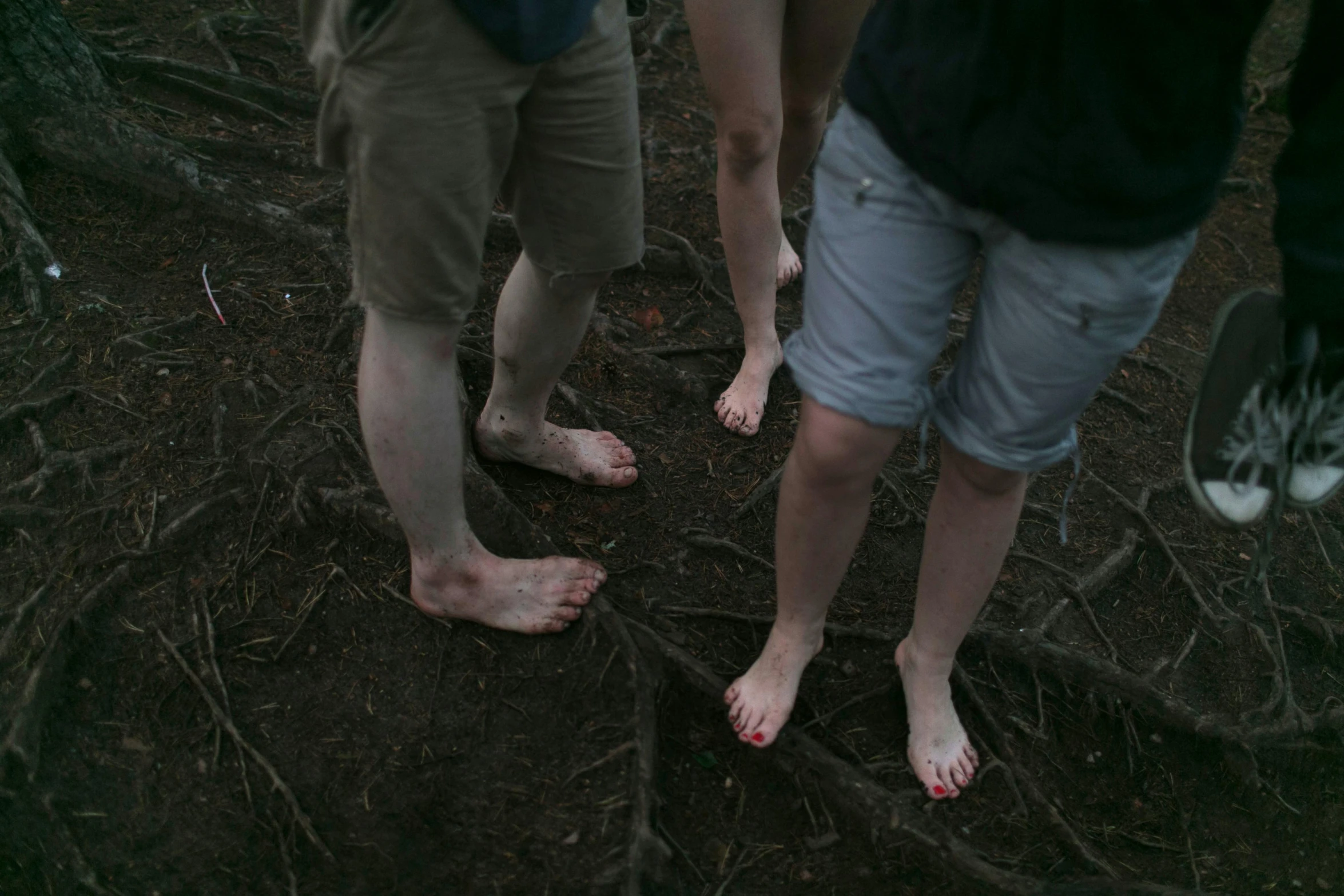 three people standing on the ground wearing bare feet