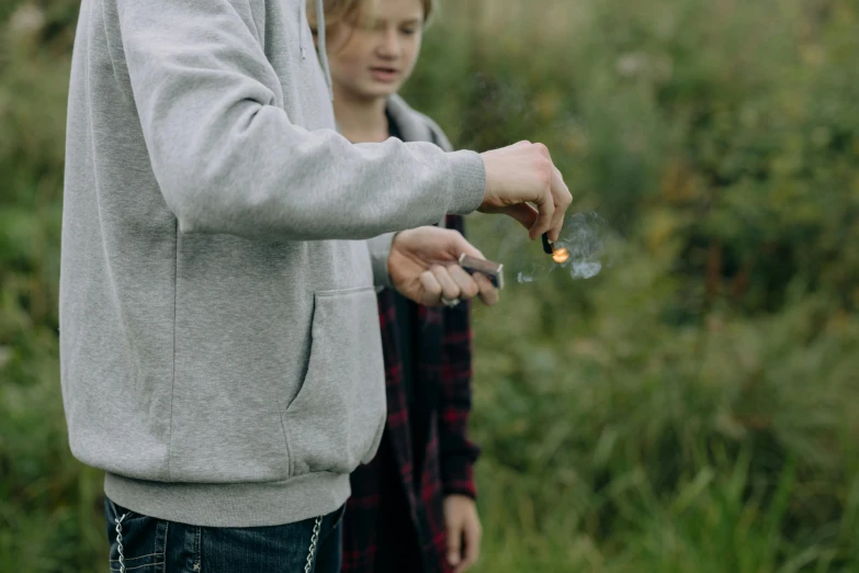 a man lighting a lit sparkler with another person behind