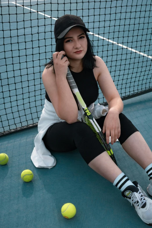 a woman sits in front of a tennis net