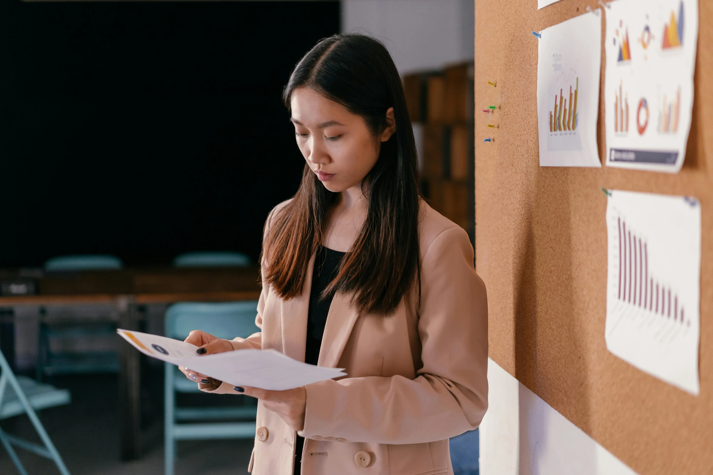 a woman in a beige blazer writing on paper