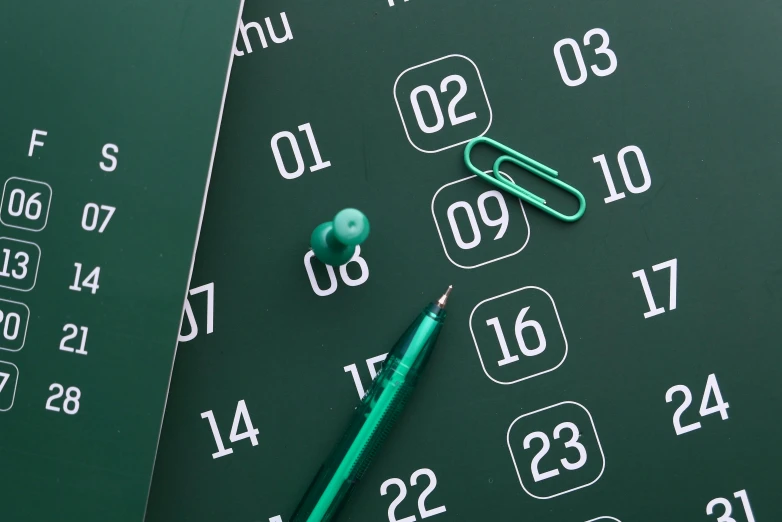 a green calendar, a green pen and several school supplies