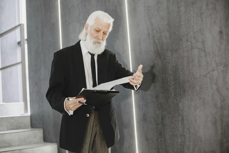 an old man in a suit holding paper and gesturing