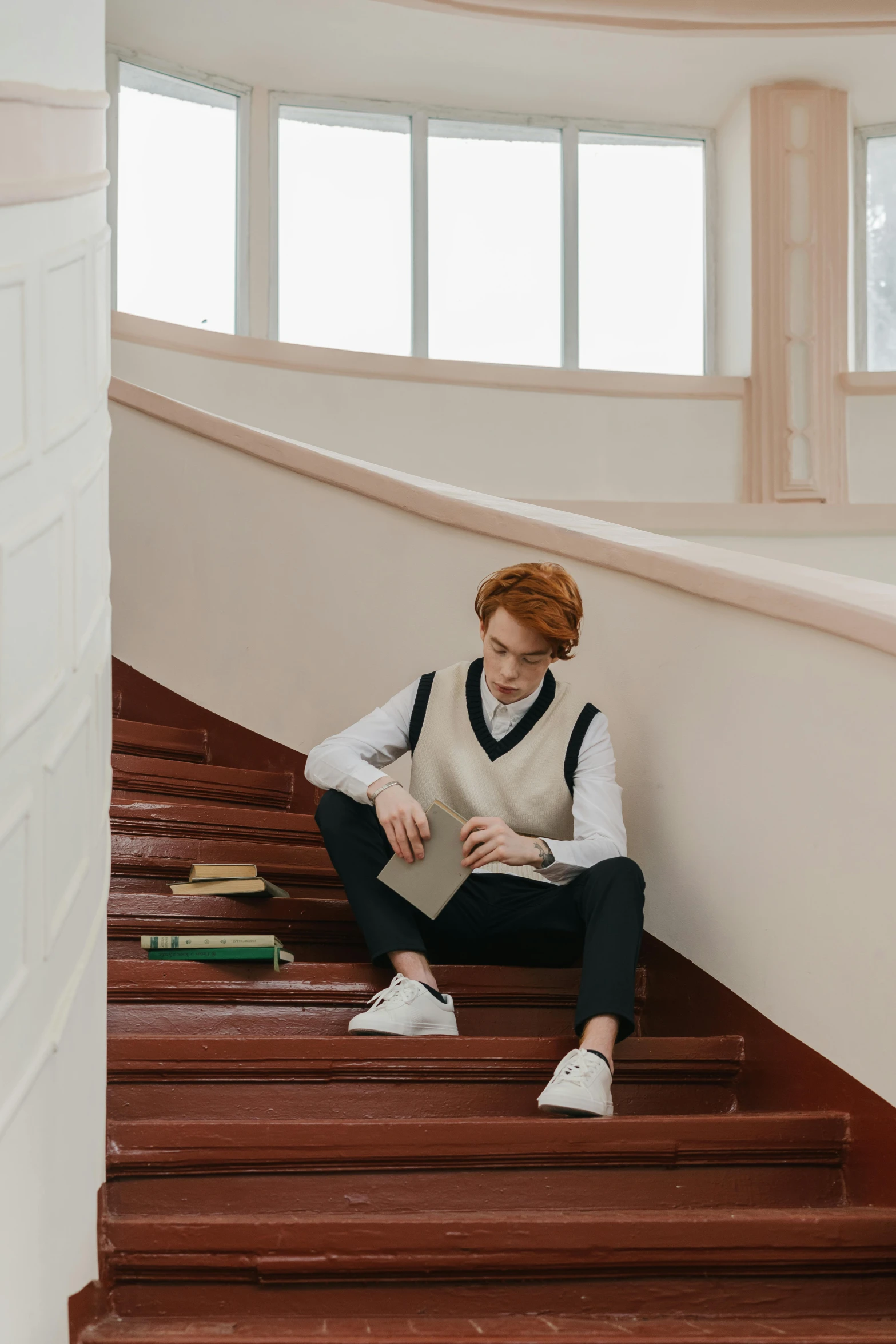 a woman sits on the ground in front of a staircase while reading a book