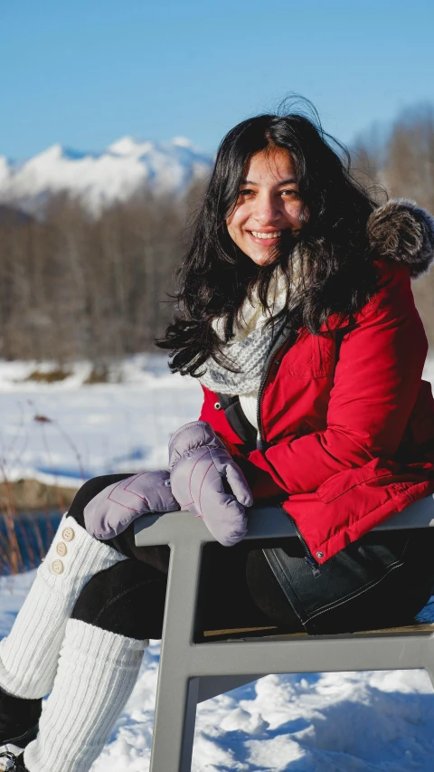 a young woman in winter clothing sitting on a bench