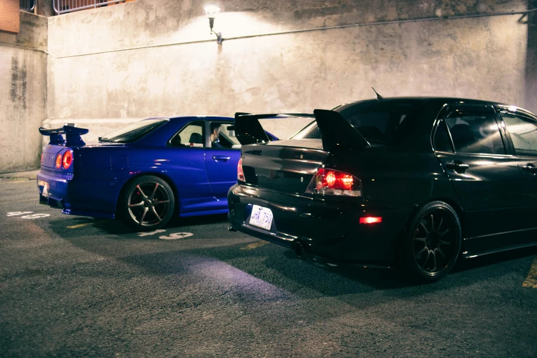 two cars are parked in an alley at night