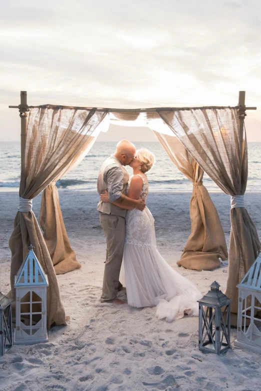 two brides emce under a rustic arch at the beach