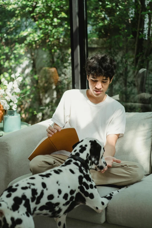 a young man holding soing out to his dog on the couch