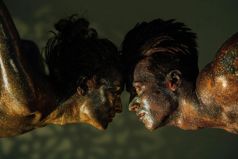 two women covered with gold and black glitter