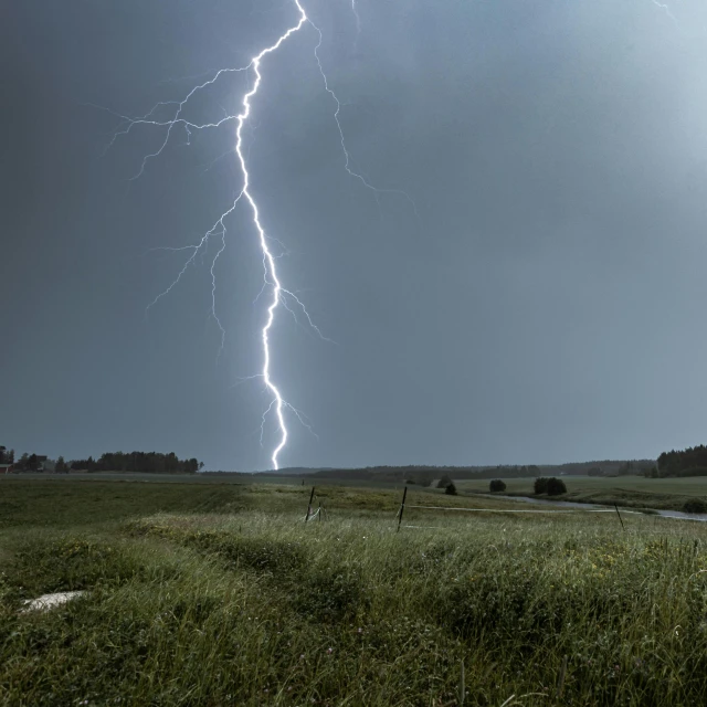 a lightning bolt strikes across the sky over an open field