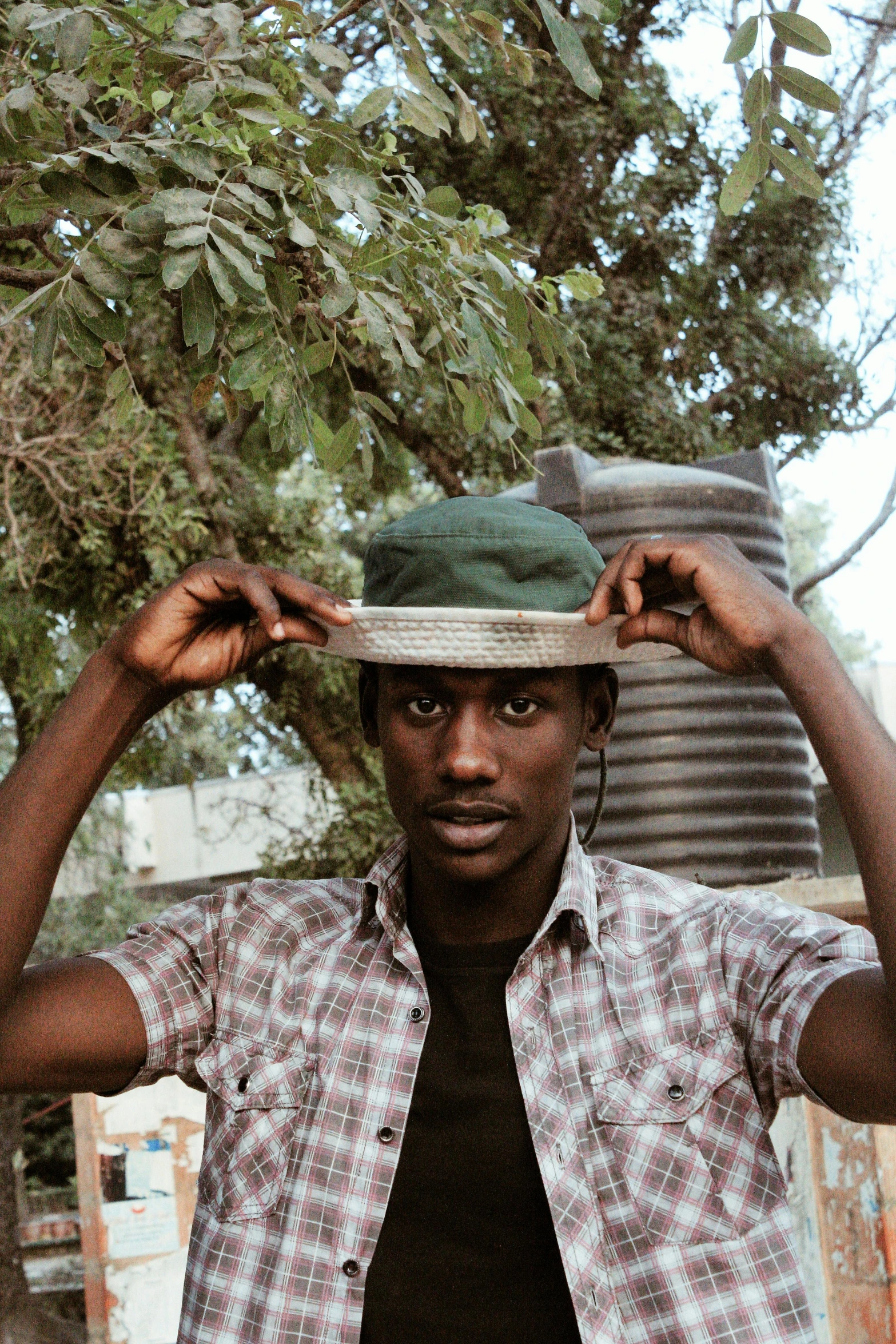 a man is holding onto a hat in front of his head