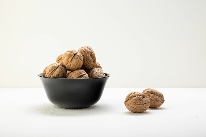 walnuts in a bowl next to some nuts on a table