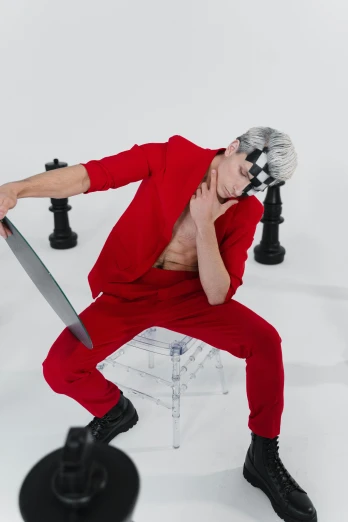 a man in red poses on a stool with a sword