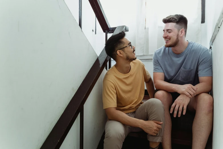 two men are sitting on the stairs and smiling