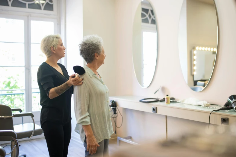 an older woman is combing another woman's hair