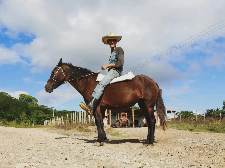 the man is riding his horse on the dirt road