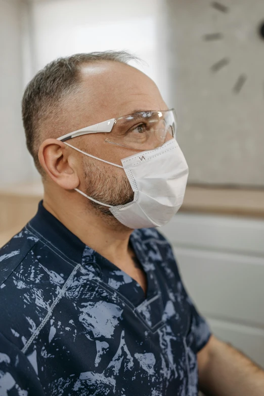 a man in a blue shirt wearing a white mask