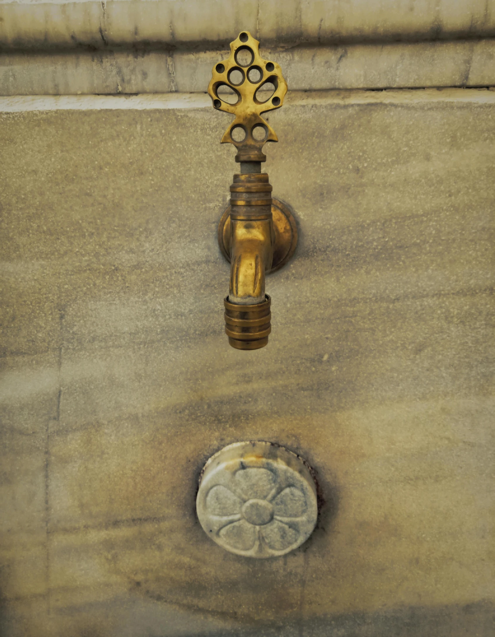 a metal faucet in front of an outside fountain