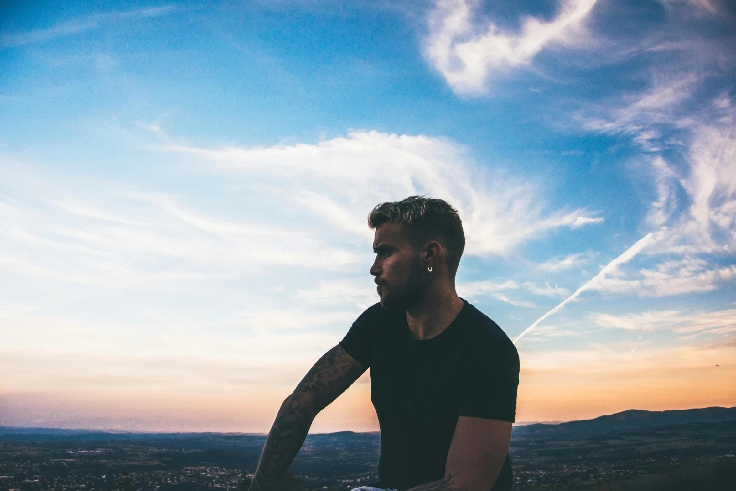 the man with a helmet stands on a hill in front of a blue sky