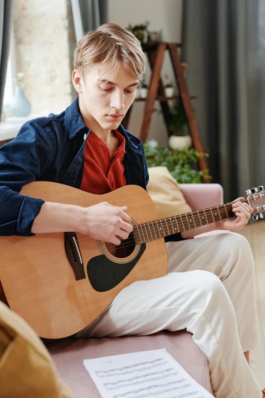 the boy is playing a guitar in his living room