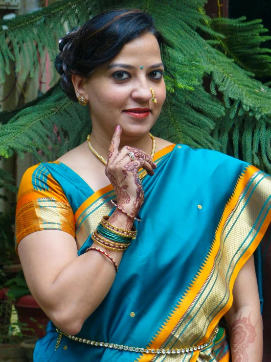 the lady wearing a blue and gold sari shows off her hand