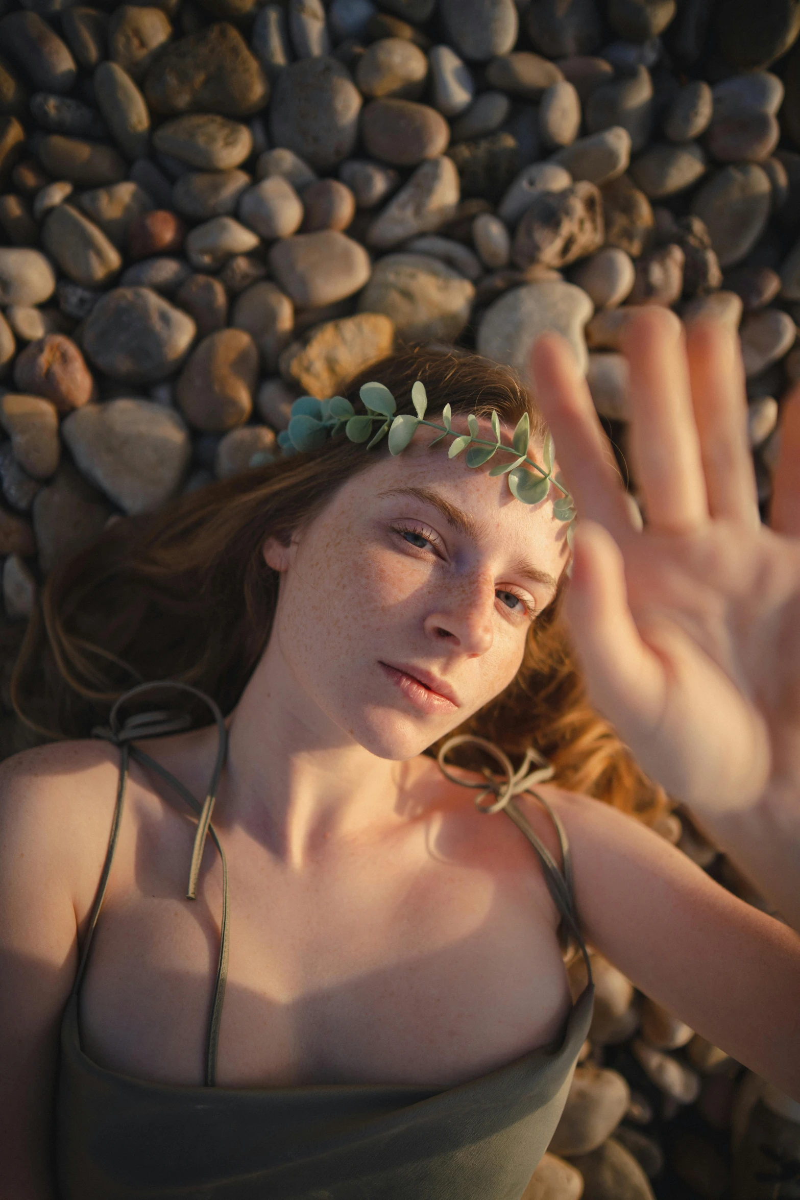 a woman wearing a flower crown holds her hand up