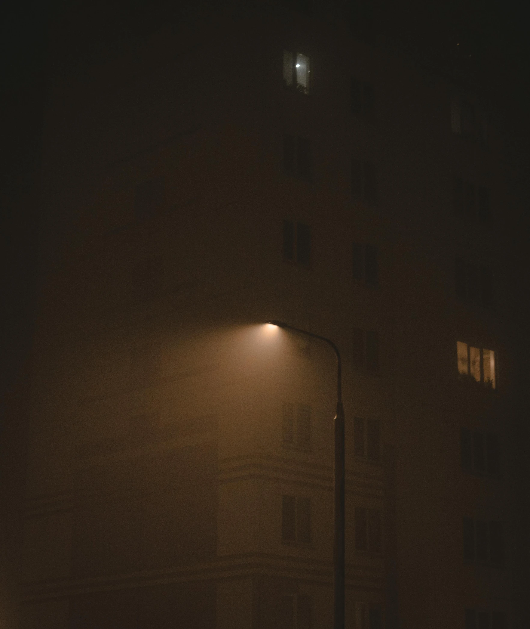 dark street with the light on in the fog