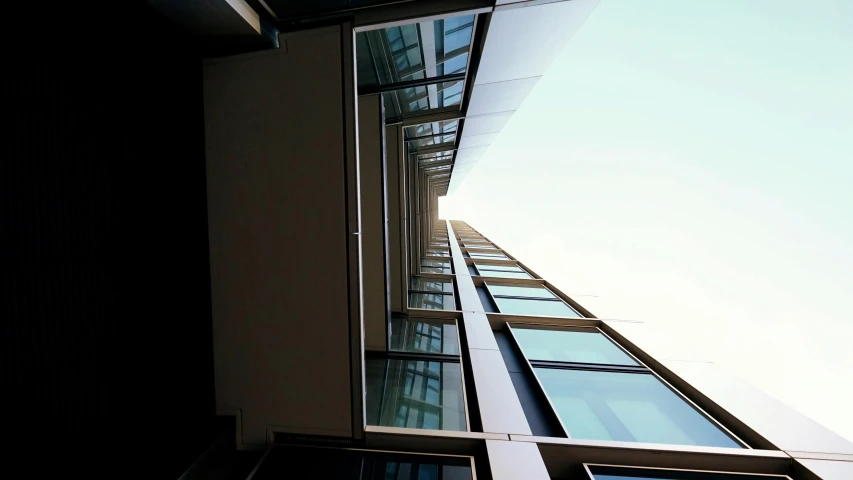 the tall building has glass windows and a sky view