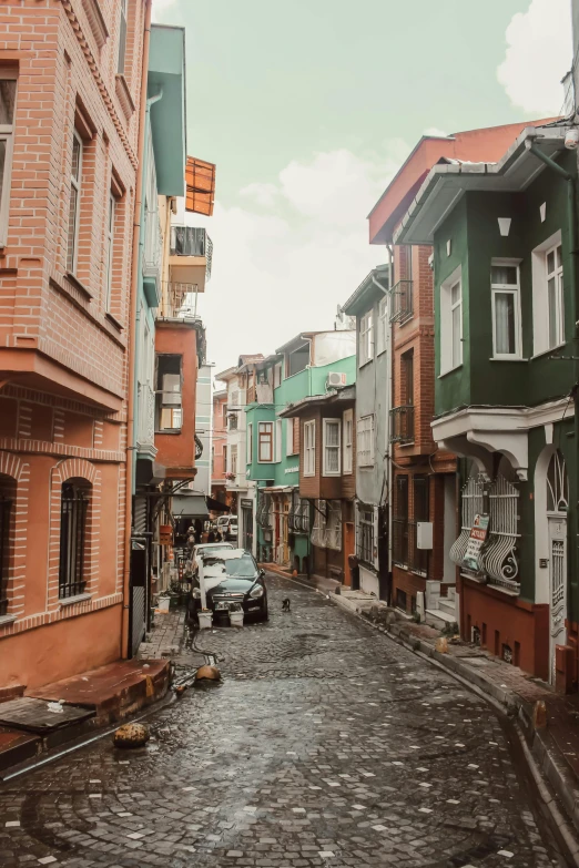 cars are parked outside colorful, brick buildings on a rainy day