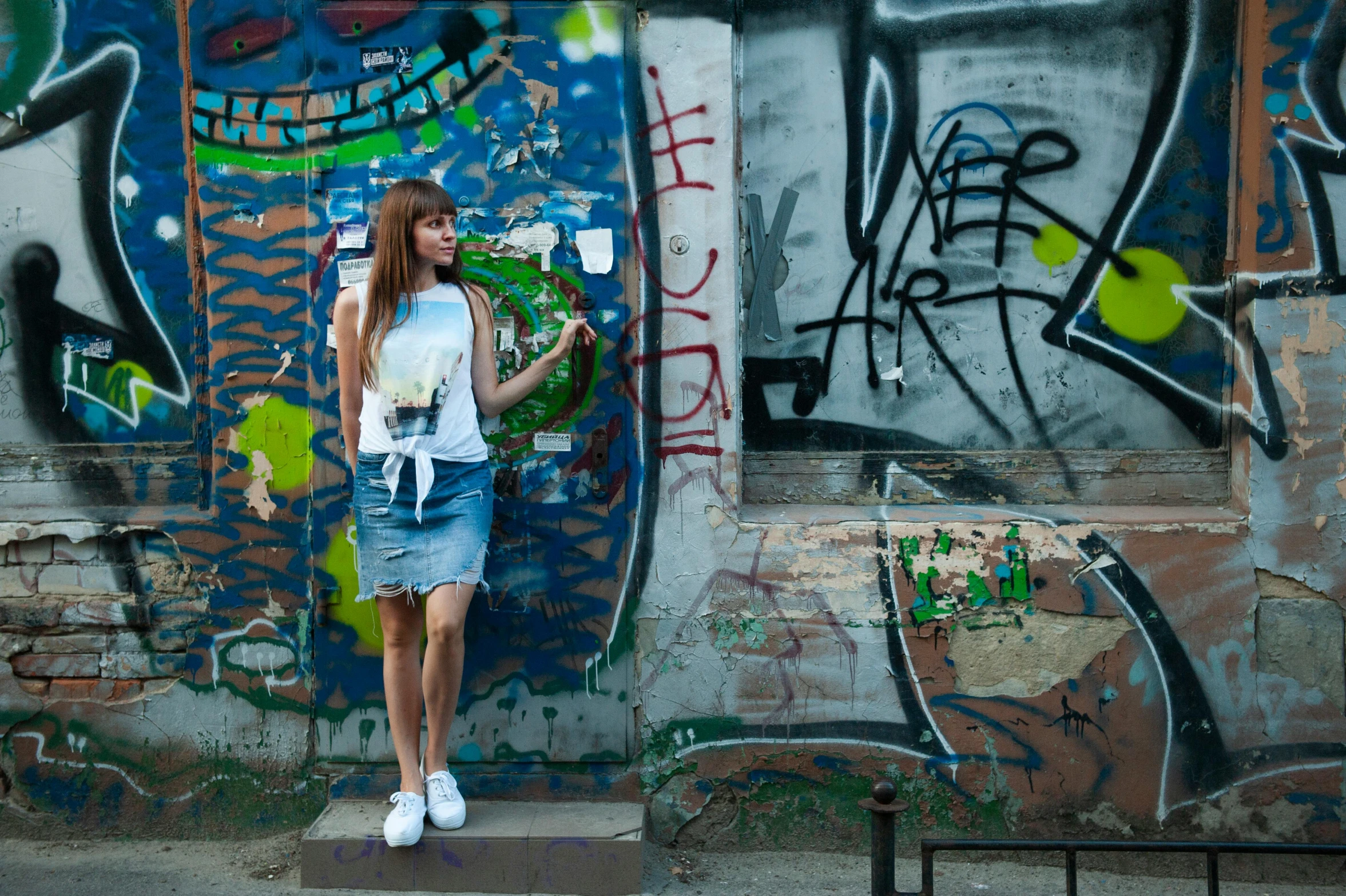 a woman is standing by a graffiti wall with her arms wrapped around her neck