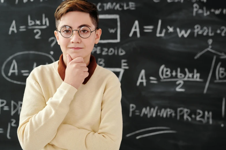a woman in glasses standing near a chalkboard with physics