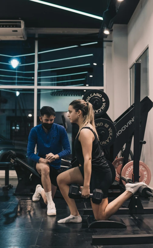 a woman and man sitting on exercise equipment in a gym