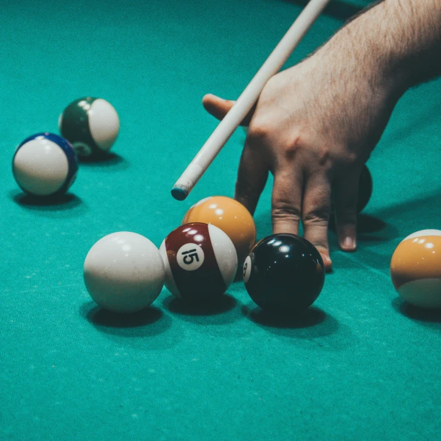 two hands reach towards some pool balls on the table