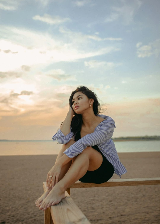 a woman sitting on a fence next to the beach