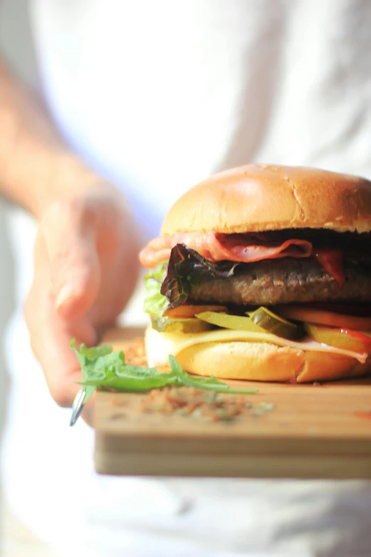 a big hamburger sitting on top of a wooden  board