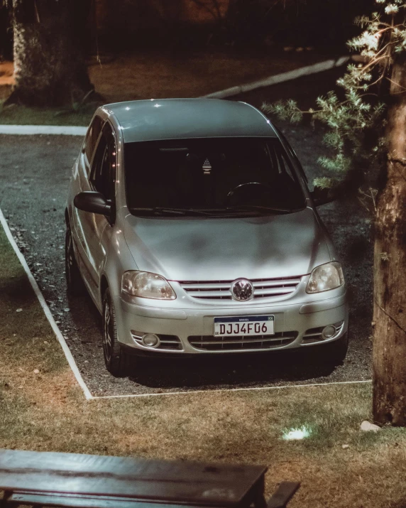 a silver car parked in a parking lot by a bench