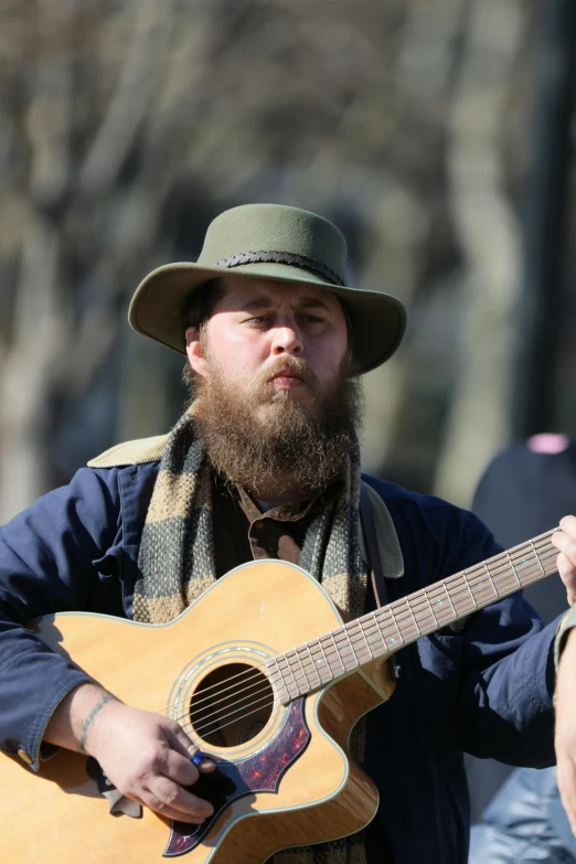 a man with a hat and a beard holding a guitar