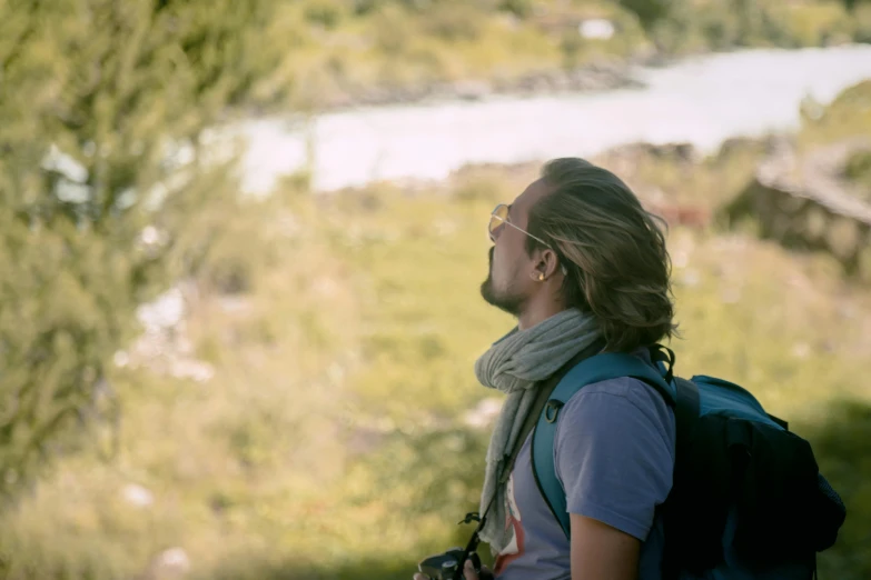 man with sunglasses and headband wearing a backpack looking up