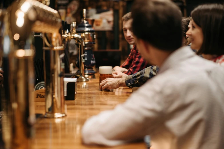 a group of people sitting at a bar with beers