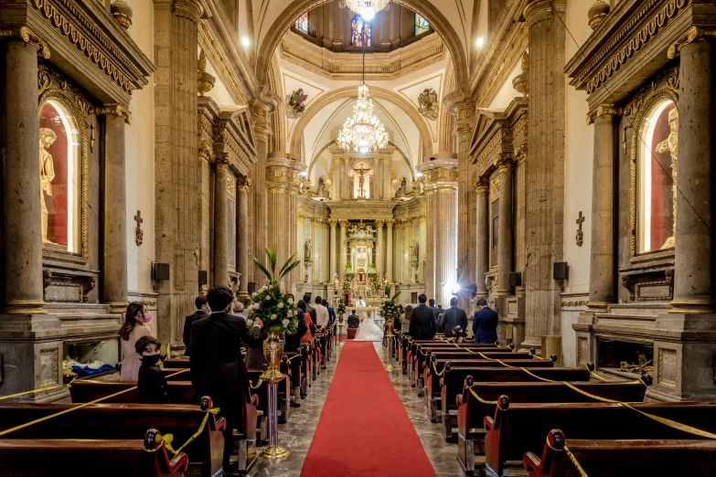 a church with pews and people standing on the side of the aisle