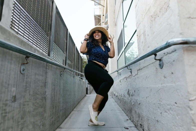 a woman in a straw hat walks down the street