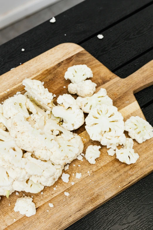 a  board topped with cauliflower on top of a table